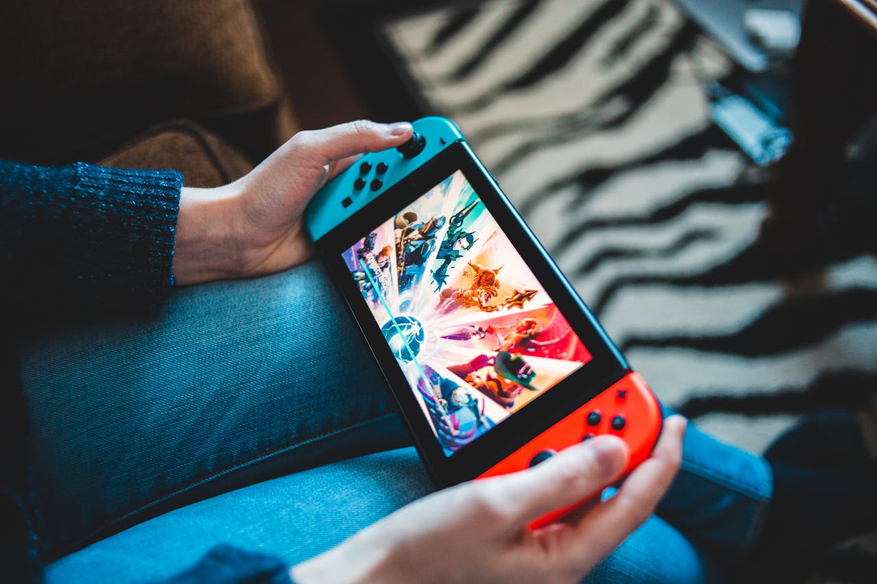 our-history-img Person gaming on a handheld Nintendo Switch console with blurred background.